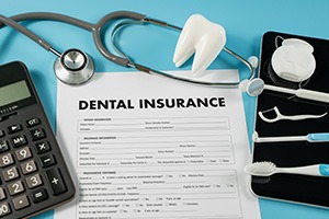 Dental insurance document next to dental instruments