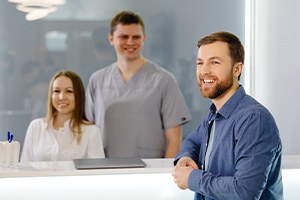 Happy man standing at dental office front desk