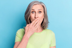 mature woman covering her mouth to hide dental stains