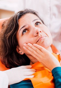 a person holding their cheek due to tooth pain