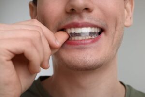 Man placing whitening strip on his teeth